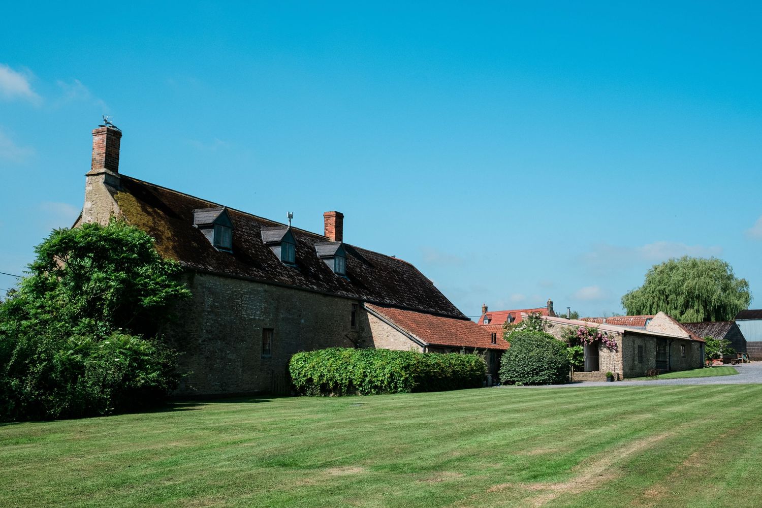 Rolling green lawns and historic stone buildings create a picturesque countryside wedding venue.