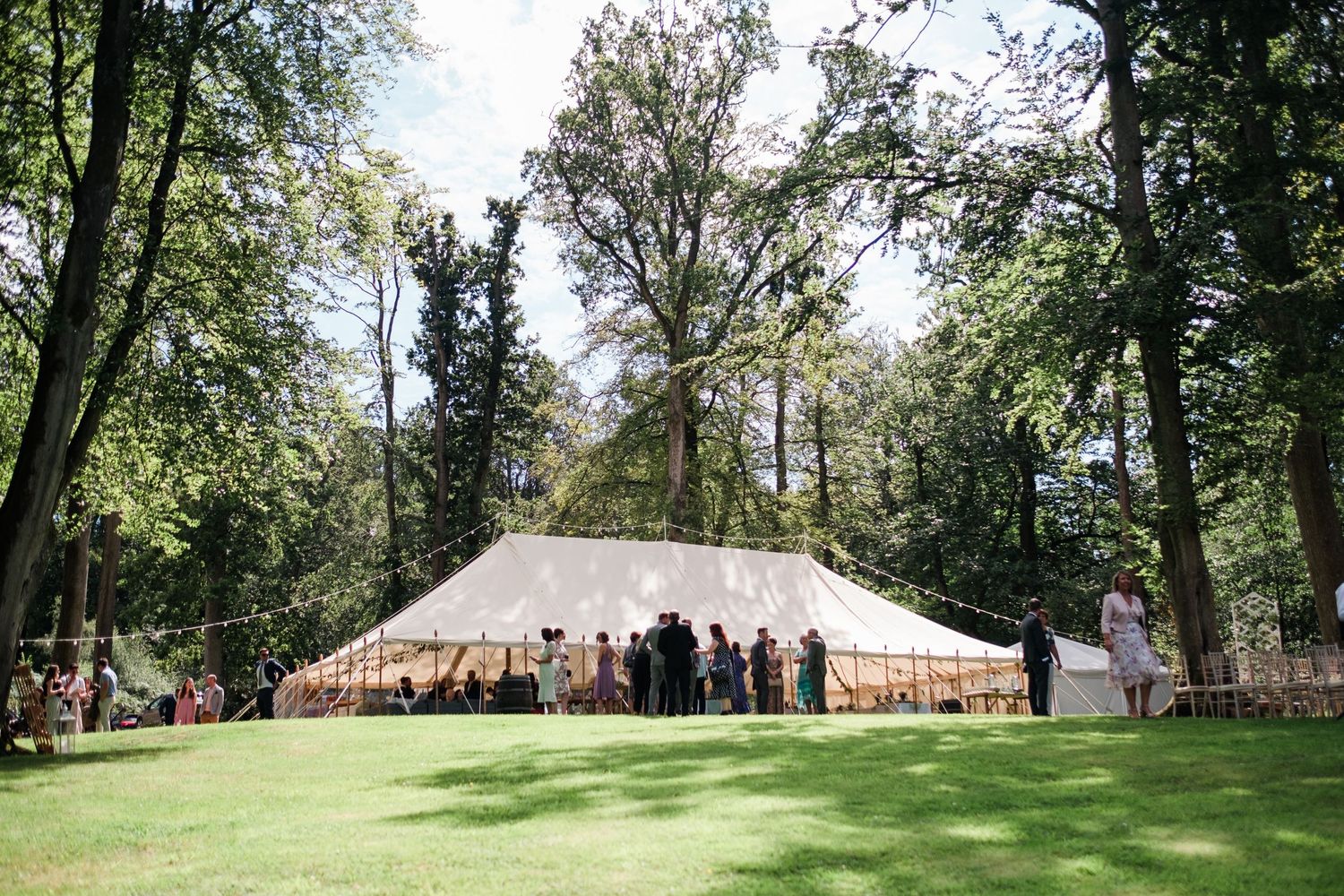 Scenic outdoor venue with green trees and white wedding tent set up on a grassy lawn.