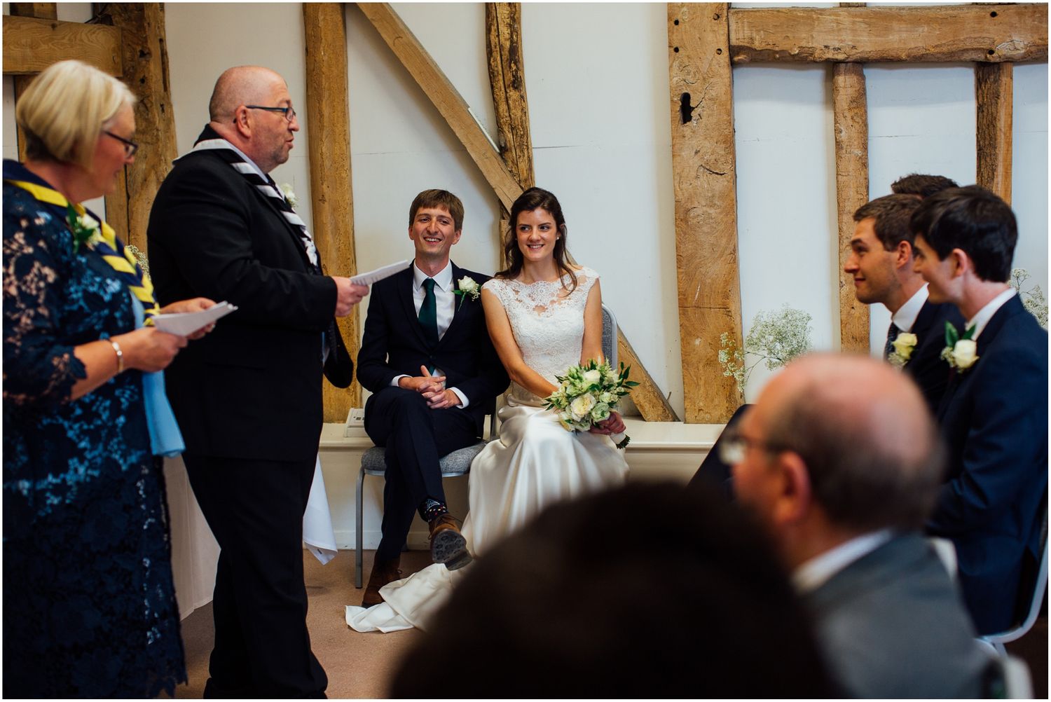 Guests gather in a rustic timber-framed venue during a wedding celebration.