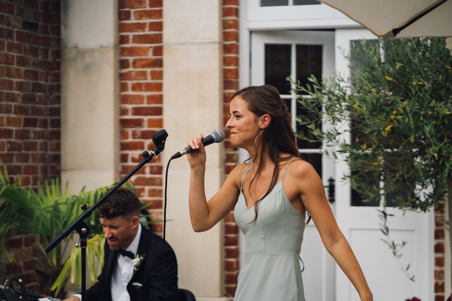 Musicians perform with microphones at an outdoor wedding venue.