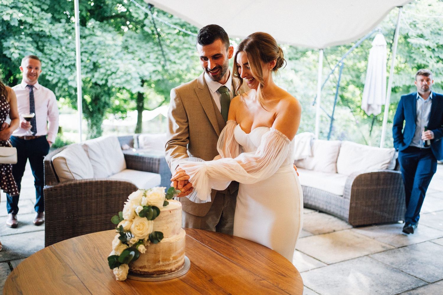 A couple signs their marriage license at a rustic outdoor venue while guests look on during the wedding ceremony.