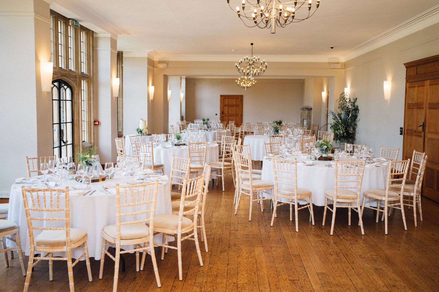 Elegant wedding reception venue with white chairs and crystal chandeliers set up for a formal dining celebration.