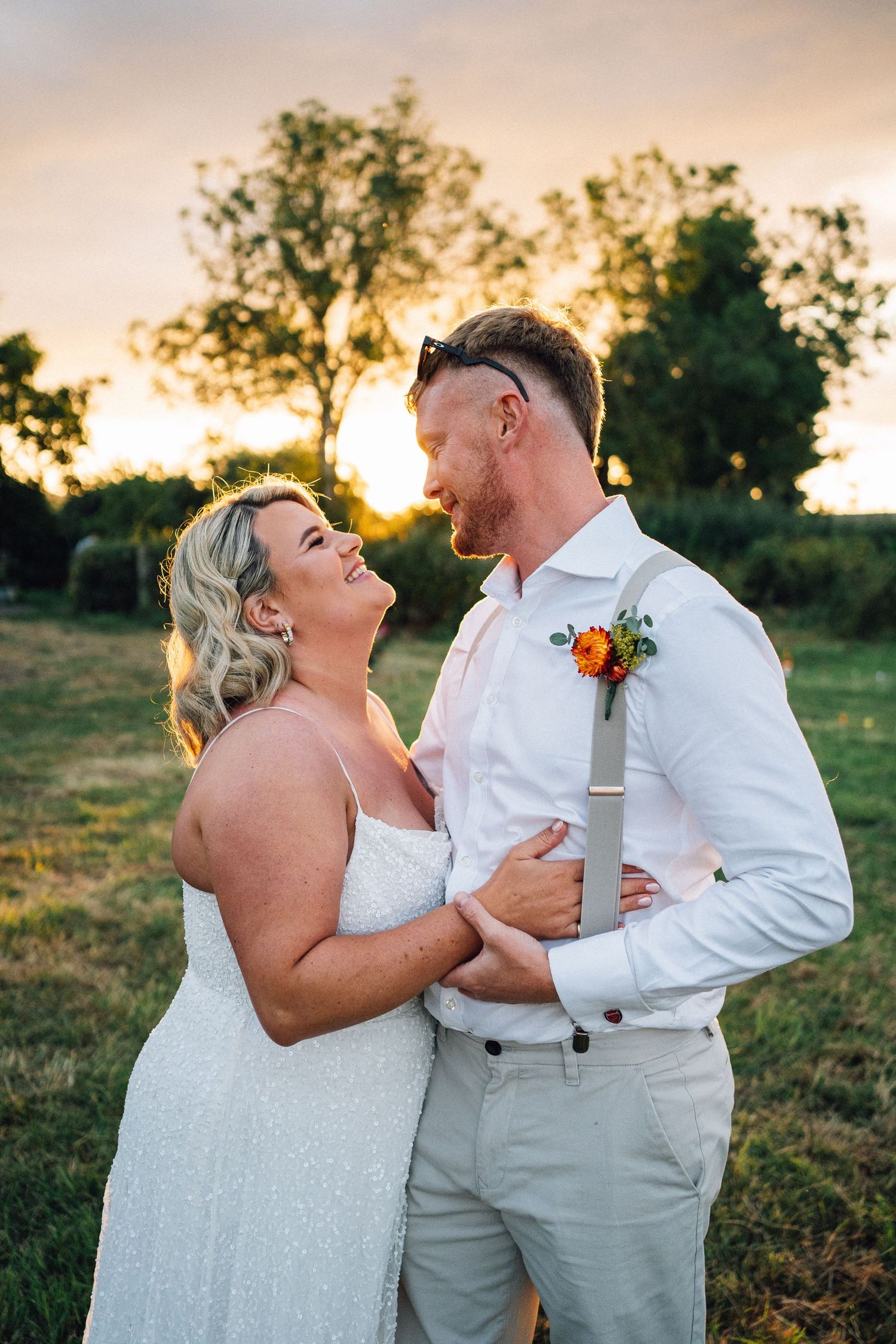 A couple shares intimate moments during sunset in a field, creating romantic wedding portraits.