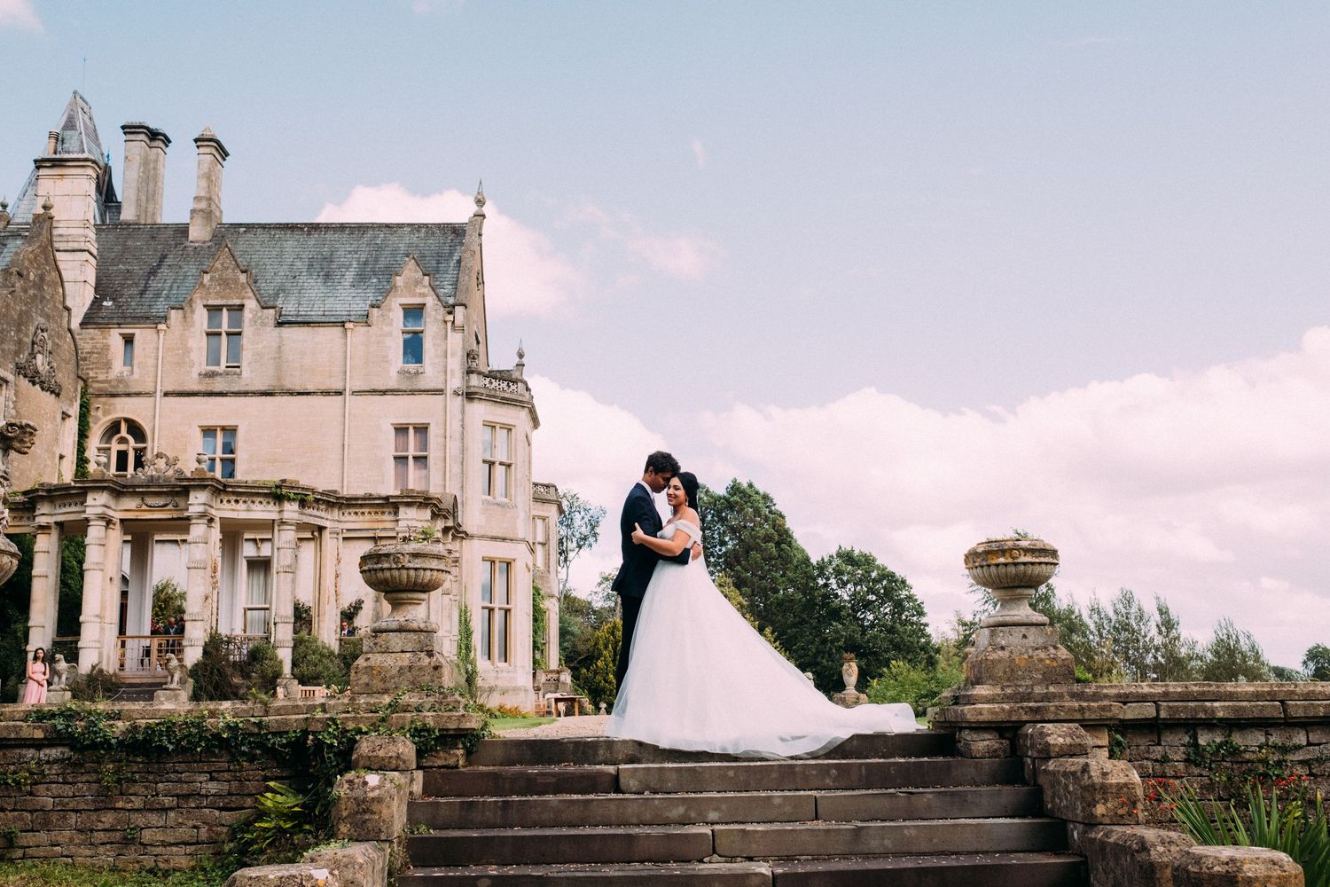 Elegant wedding venue exterior featuring stone architecture and romantic landscaping at sunset.