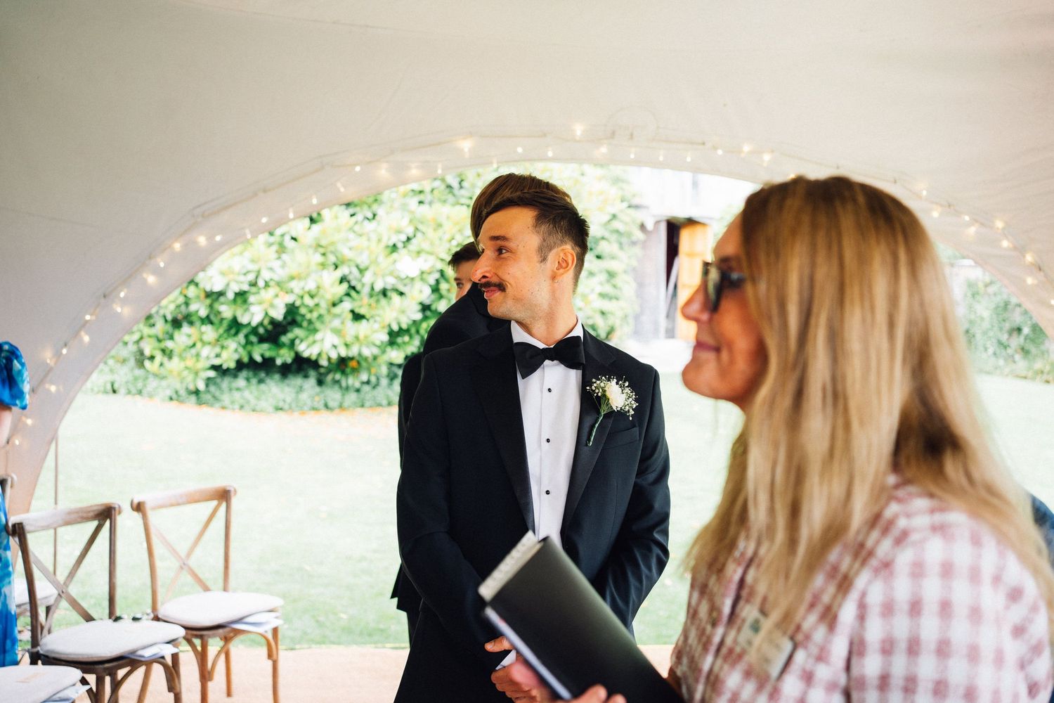 Wedding reception celebration under a white tent with string lights.