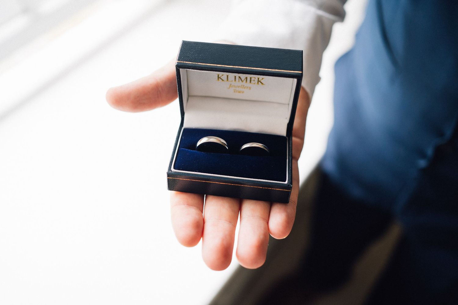 Close-up shot of wedding rings in a navy blue presentation box.