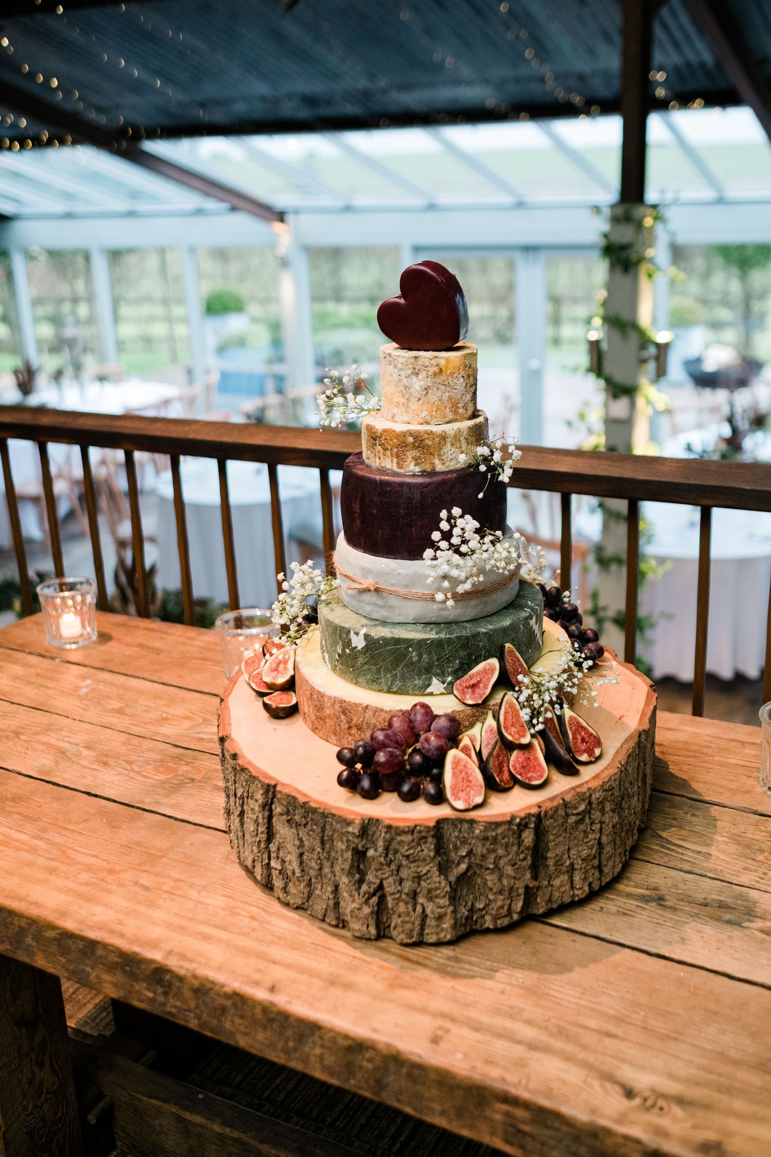 Rustic wedding cake display on wooden tree slices decorated with figs and greenery.