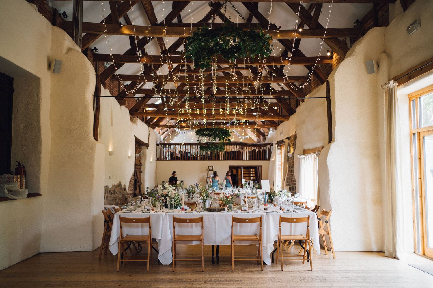 Elegant wedding reception venue with exposed wooden beams and white table settings.