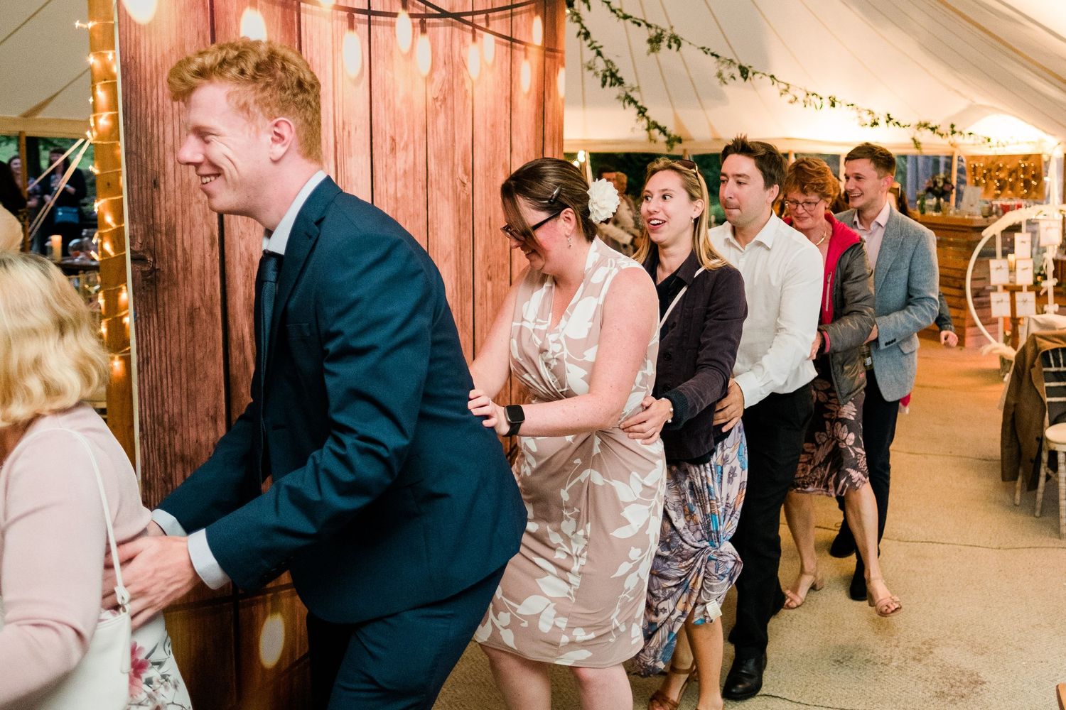 Guests dance and celebrate inside a rustic wooden barn decorated for a wedding reception.