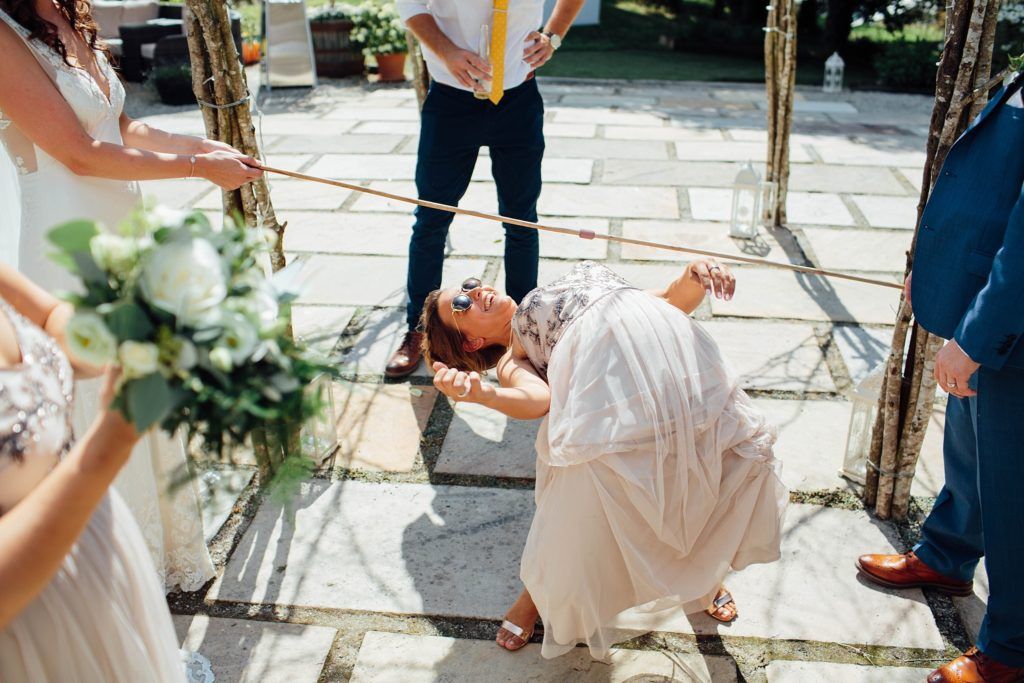 A person in white bends backward dramatically during a playful moment at an outdoor celebration.