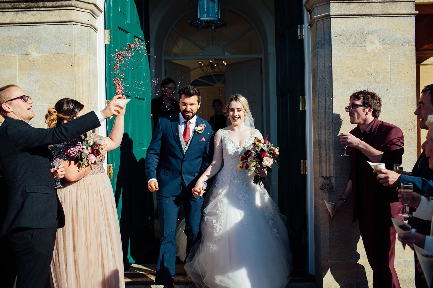 Joyful wedding celebration outside a classic stone building with green architectural details.