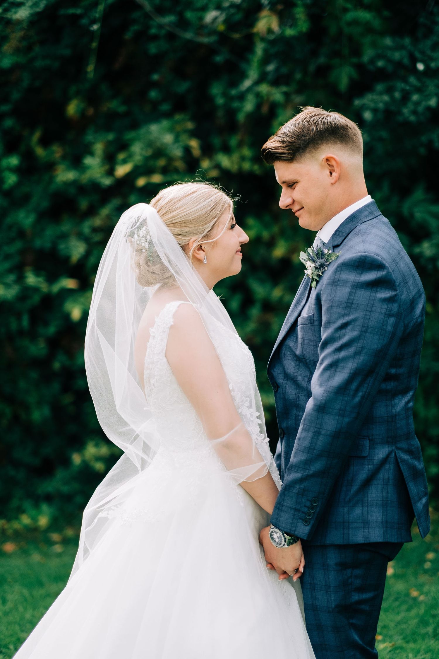 Romantic wedding couple shares intimate moment in garden setting.