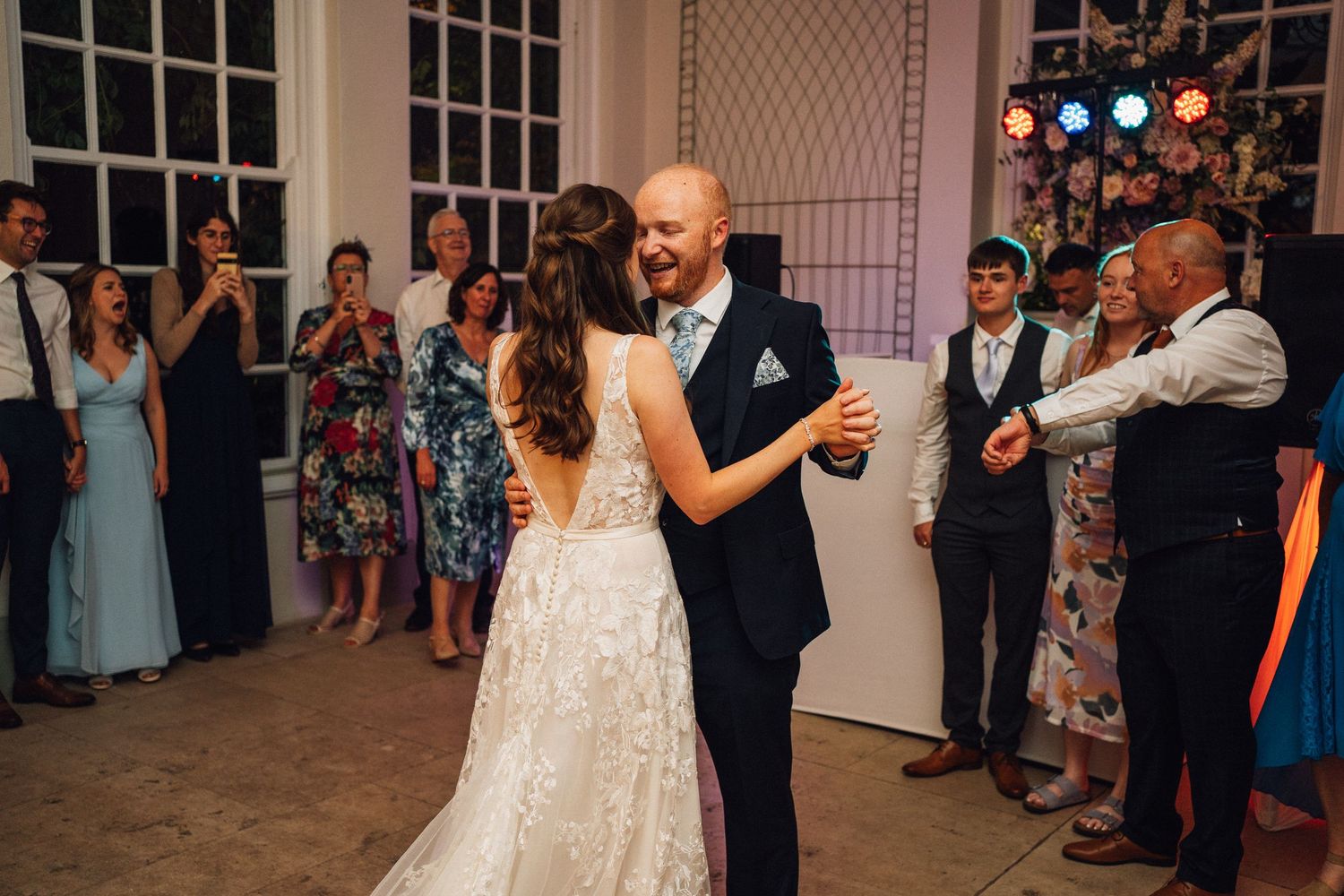 Wedding guests dance and celebrate together at an elegant indoor reception venue.