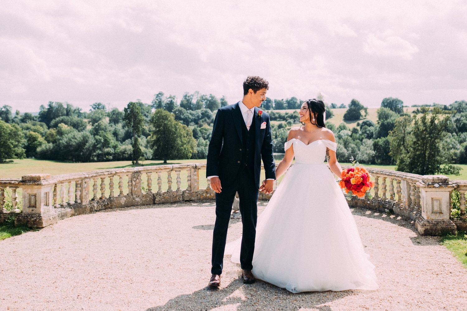 Bride and groom sharing intimate moment on grand estate balcony.