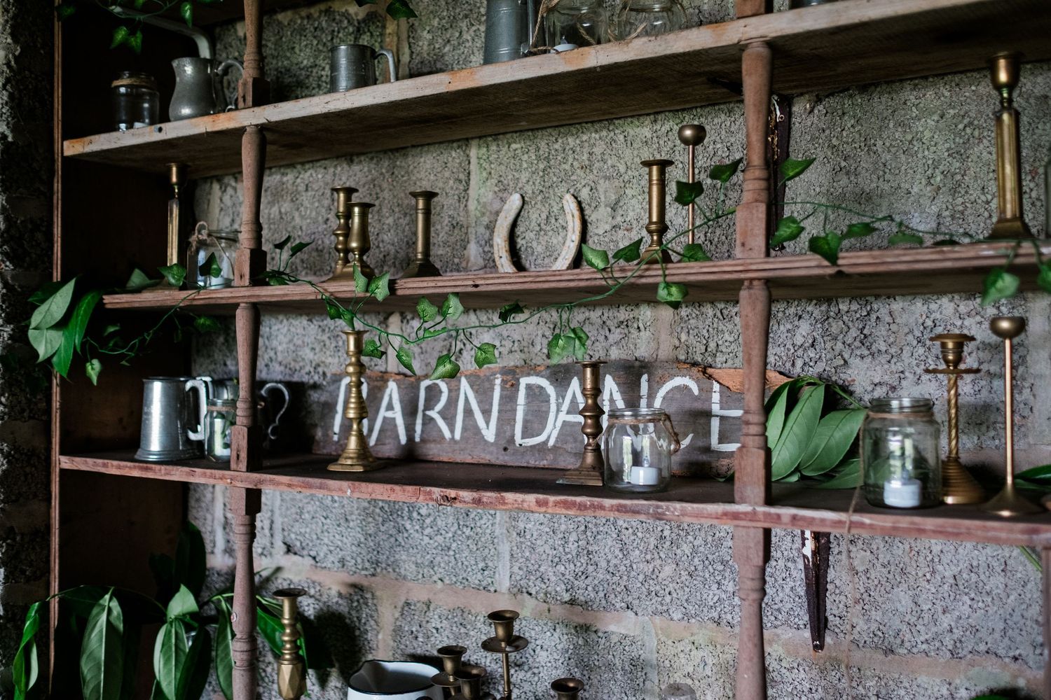 Rustic barn wall decorated with vintage trophies, horseshoes, and equestrian memorabilia on wooden shelves.