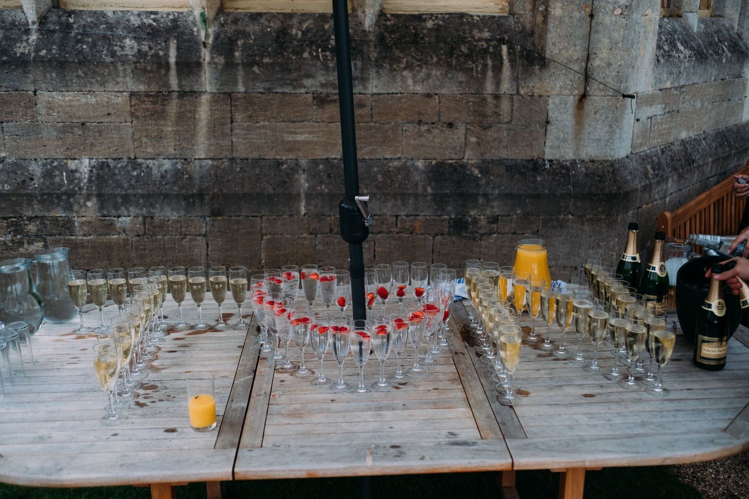 Long row of champagne glasses set up against a stone wall for a wedding reception.