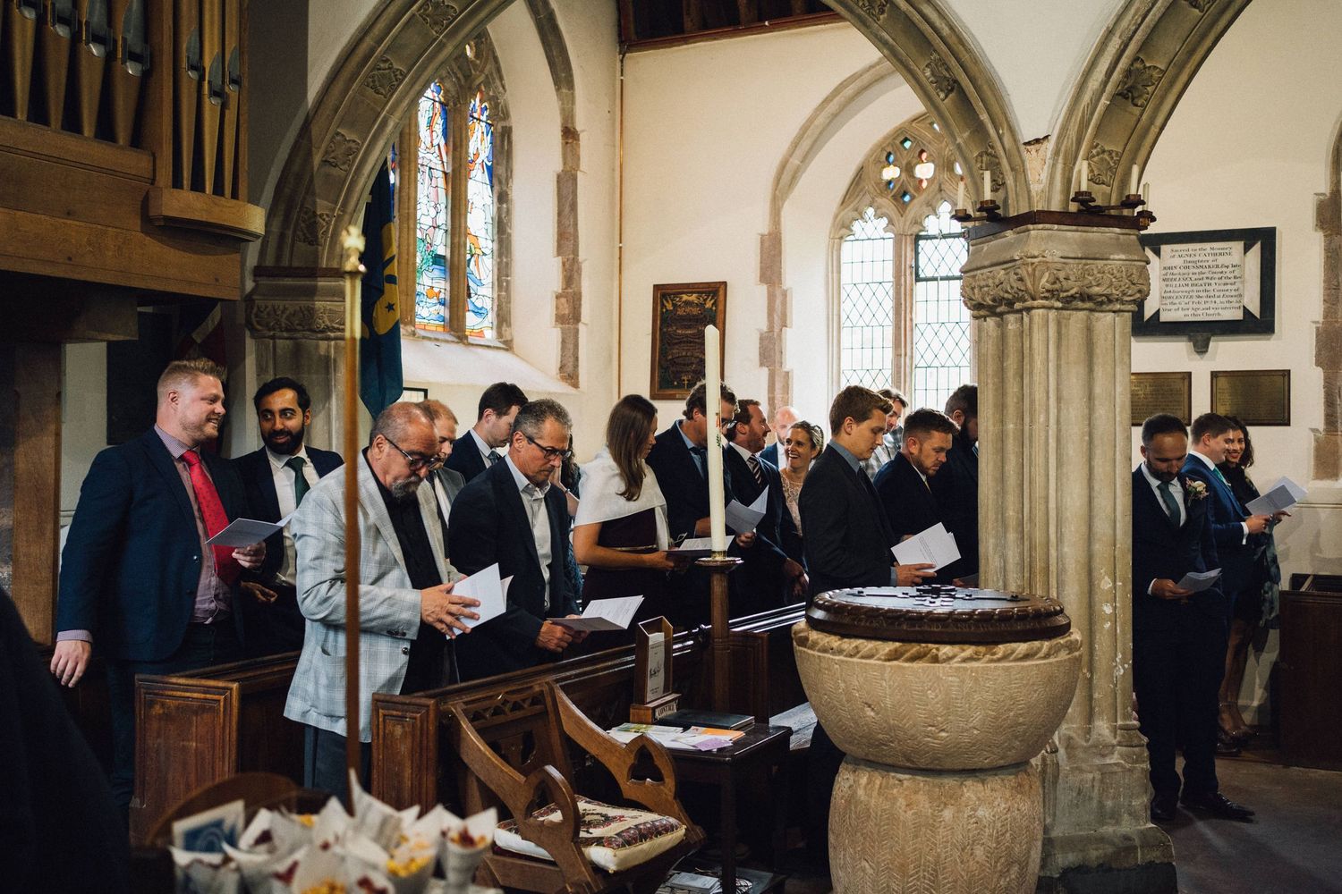 Wedding guests gathered in a stone-arched church hallway during celebration.