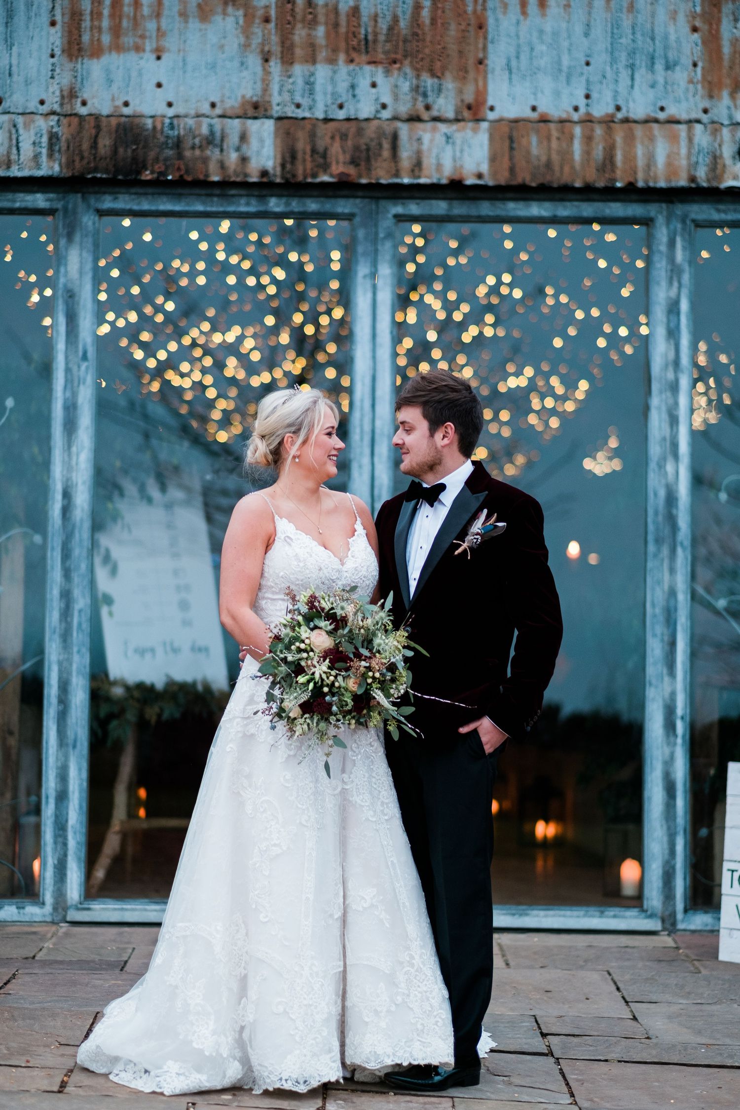 Wedding portraits against an industrial blue wall with twinkling lights creating a romantic atmosphere.