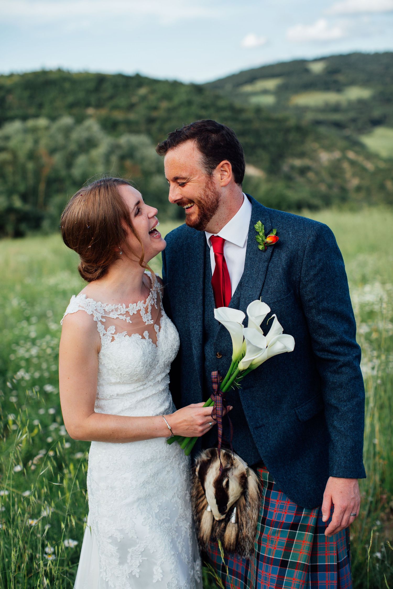 A romantic moment captured between newlyweds in a wildflower field with mountains in the background.