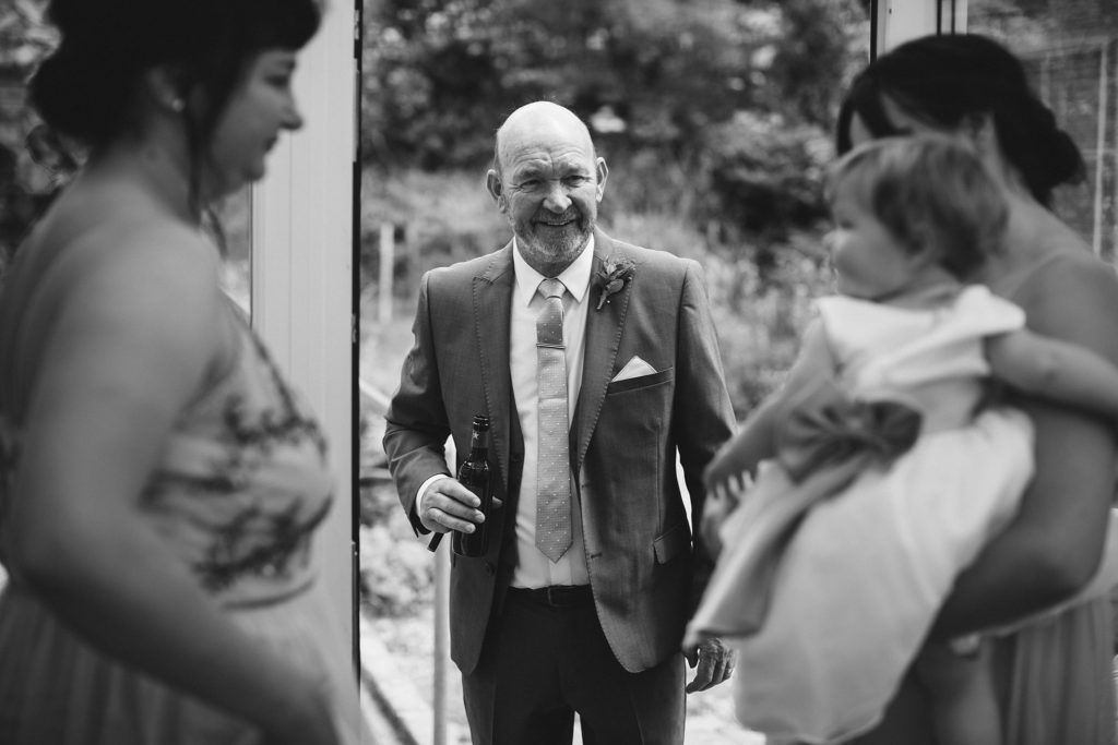 Black and white photo of wedding guests dancing and celebrating at reception.