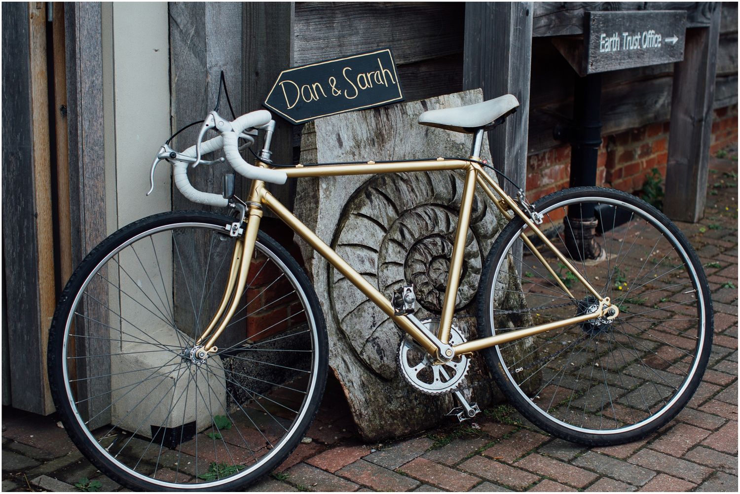 Vintage bicycles parked against a stone wall with rustic signage.