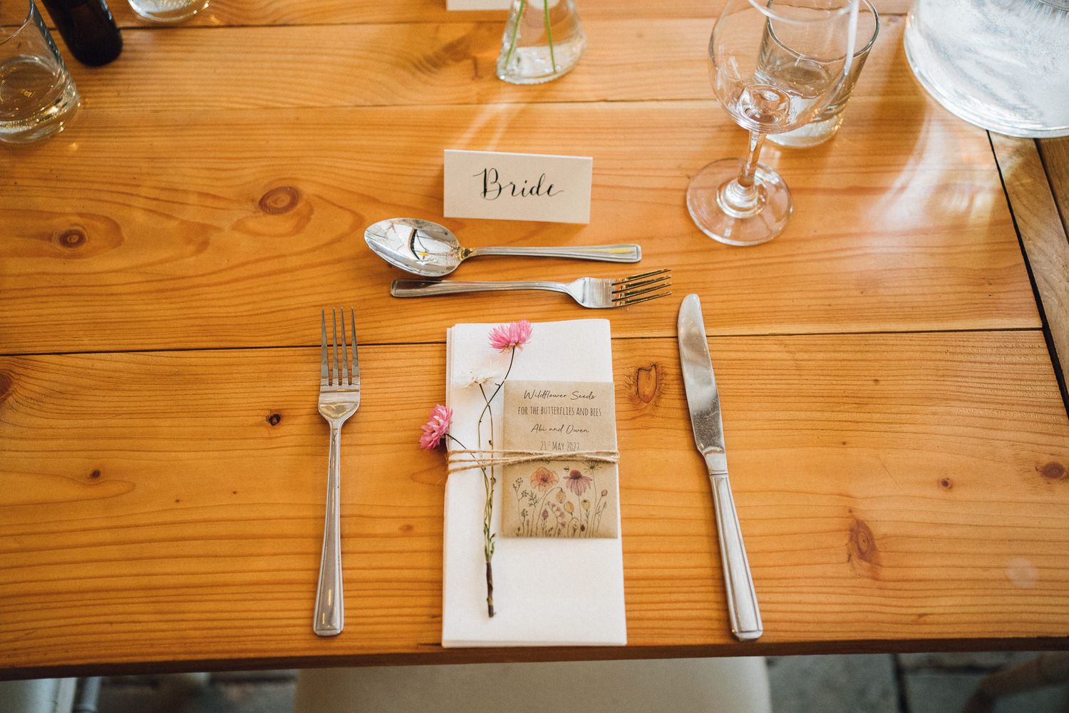 Rustic wooden table setting with wine glasses and place settings at wedding reception.