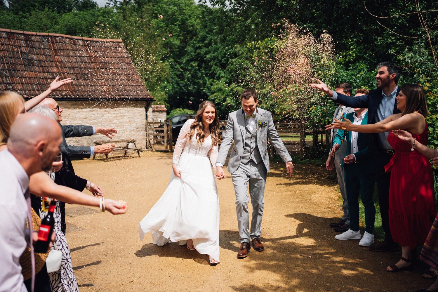 Wedding party and guests gather outside a rustic venue for celebration.