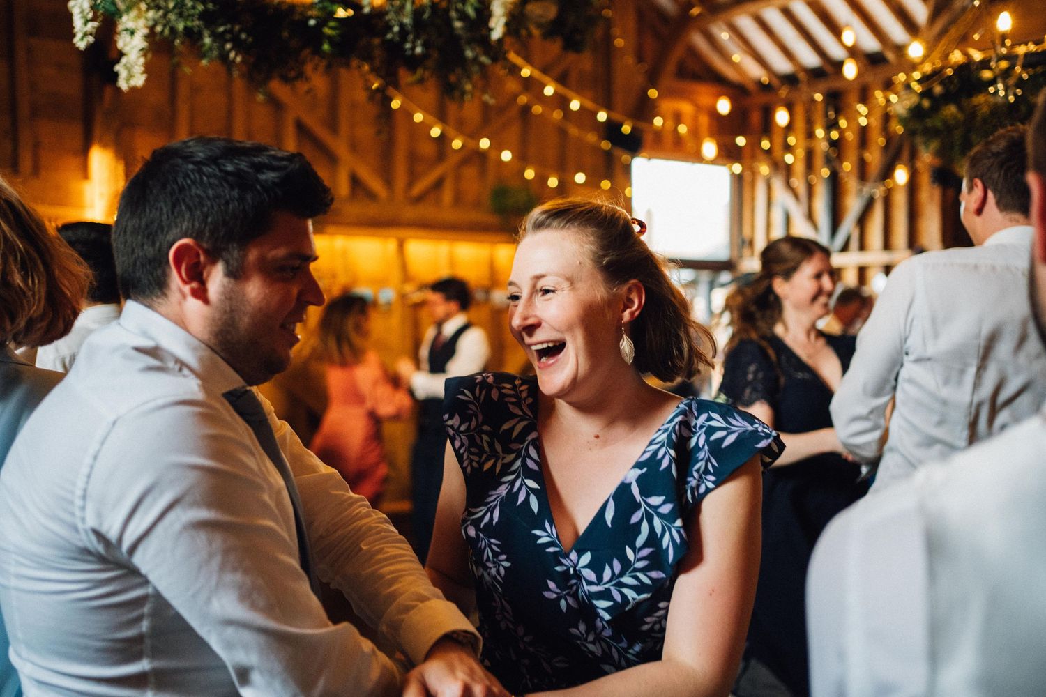 Wedding reception dance floor filled with guests celebrating under string lights and greenery.