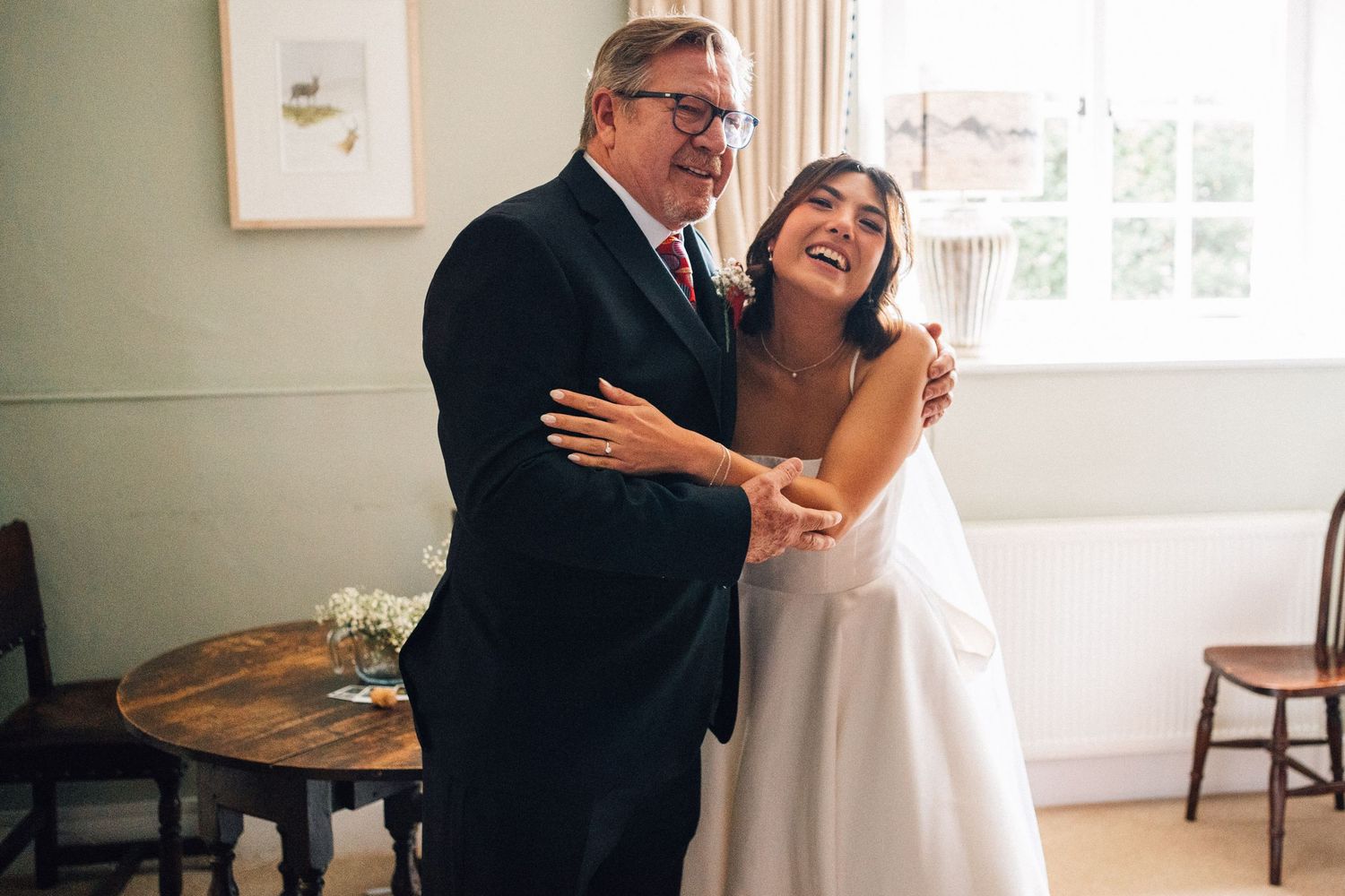 A joyful moment shared between two people in formal attire by a bright window.