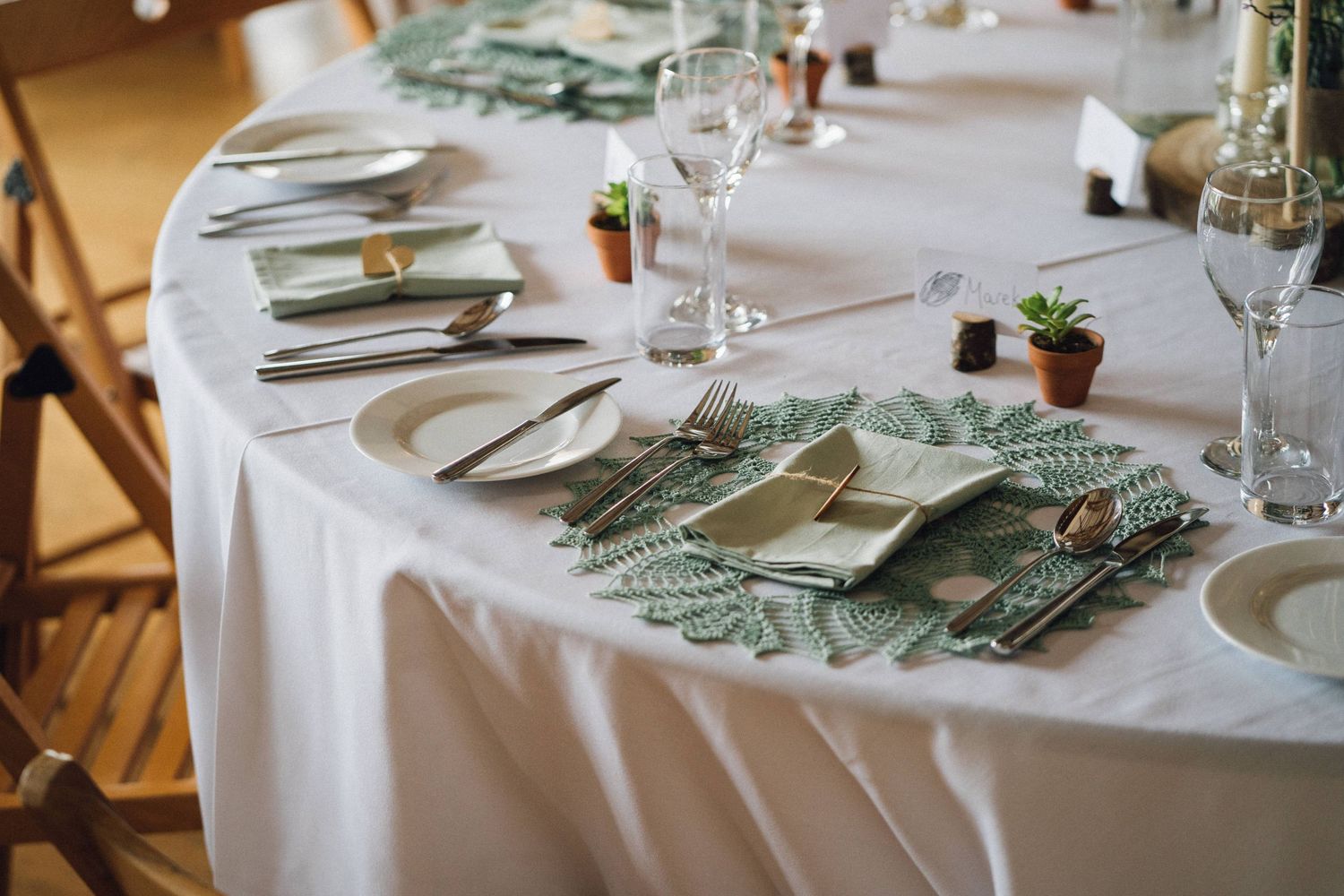 Wedding reception tables decorated with white linens and greenery centerpieces.