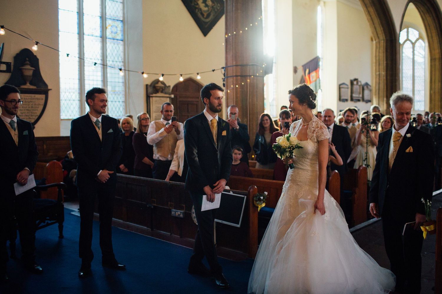 A wedding ceremony takes place in a church with beautiful arched windows and traditional decor.