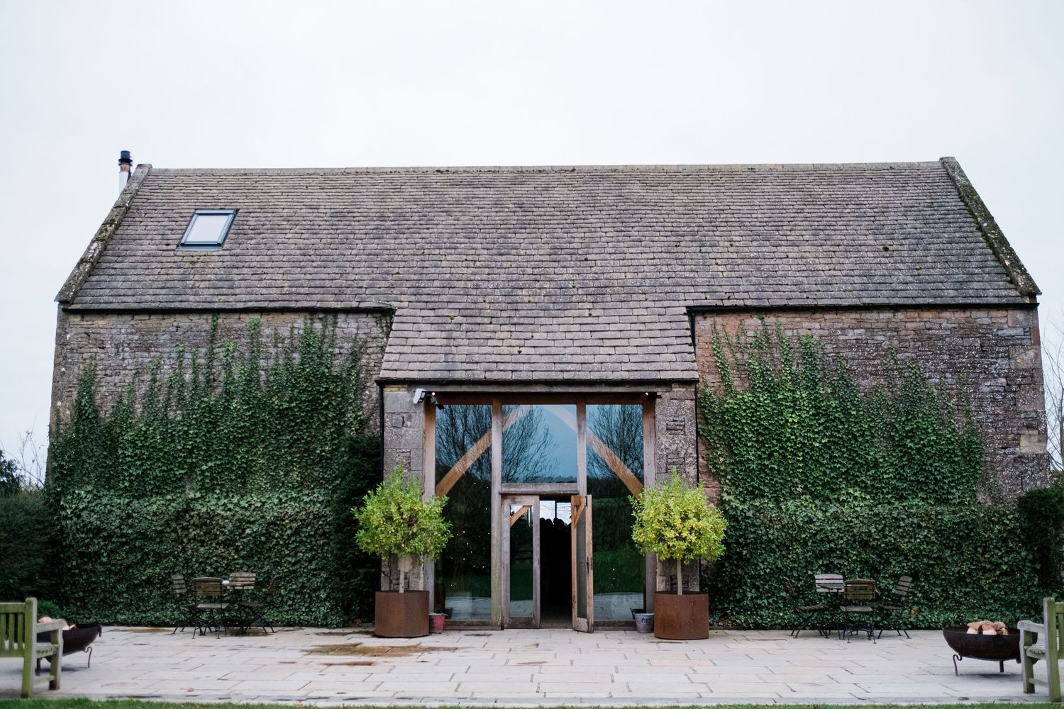 Exterior view of a rustic stone barn venue with multiple entrances and windows.