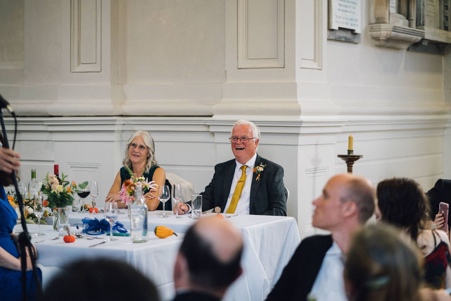Wedding reception guests raising glasses in celebration at an elegant indoor venue.