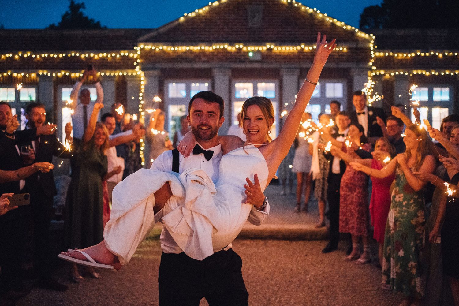 Wedding venue exterior illuminated with string lights against a deep blue evening sky.