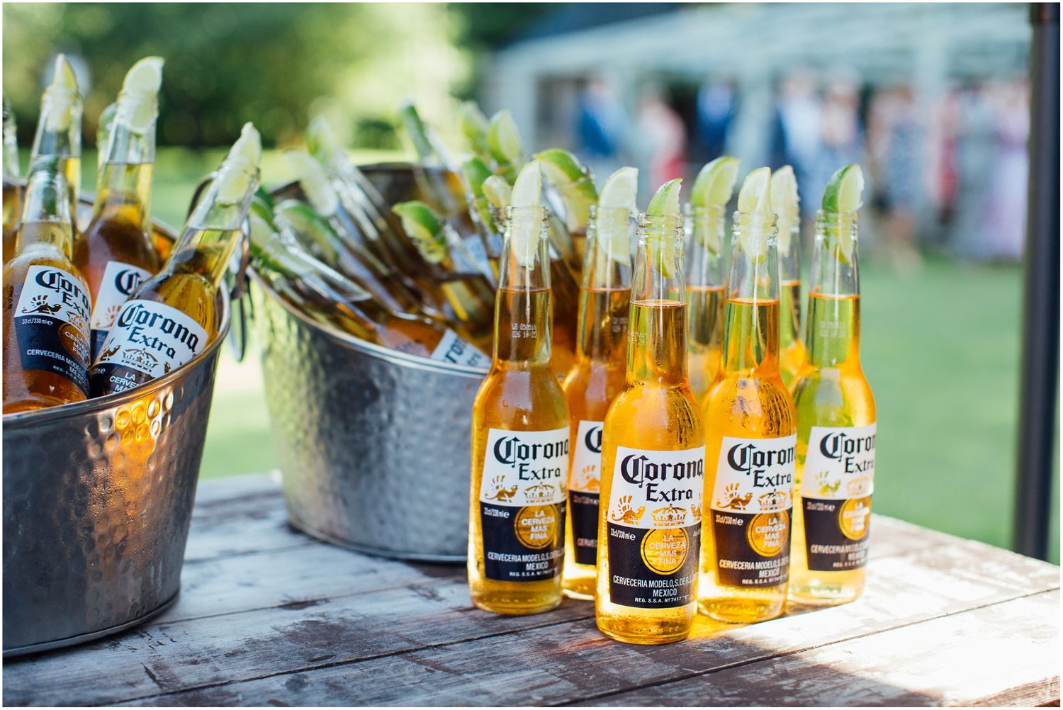 Corona beer bottles arranged in ice buckets at outdoor wedding reception.