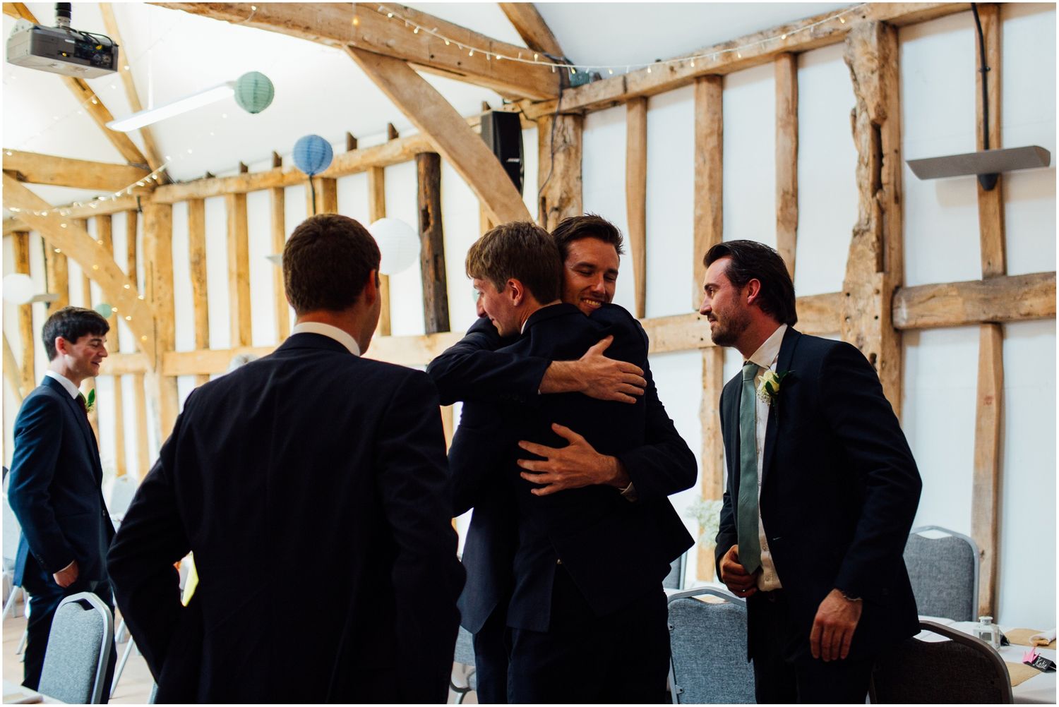 Wedding guests mingling in a bright timber-framed reception venue.