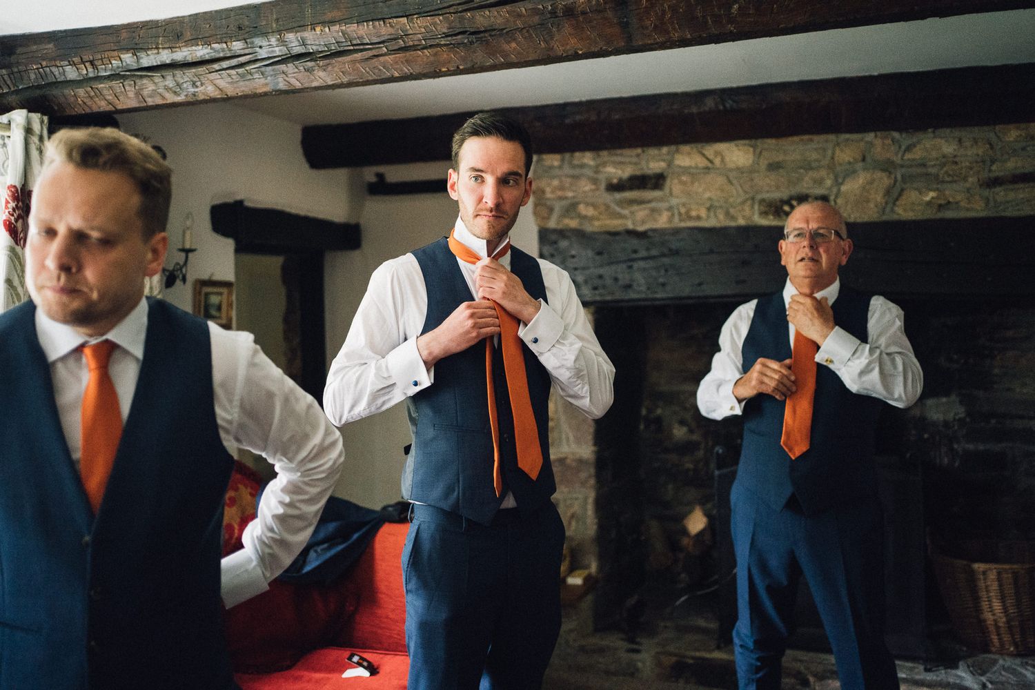 Wedding party members adjusting ties and preparing formal attire indoors.