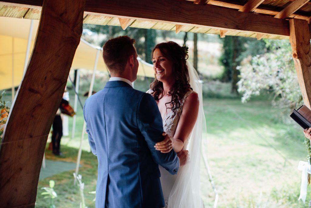 A couple dances together under a rustic wooden pavilion at their wedding.
