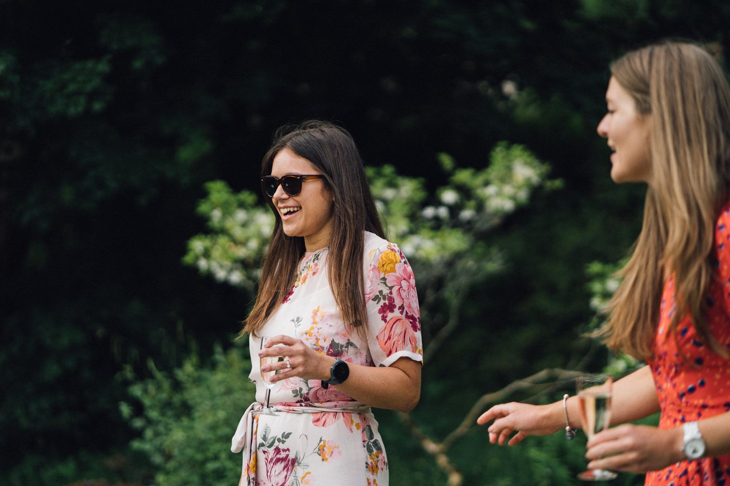 Wedding guests in summer attire enjoying conversation at outdoor celebration.