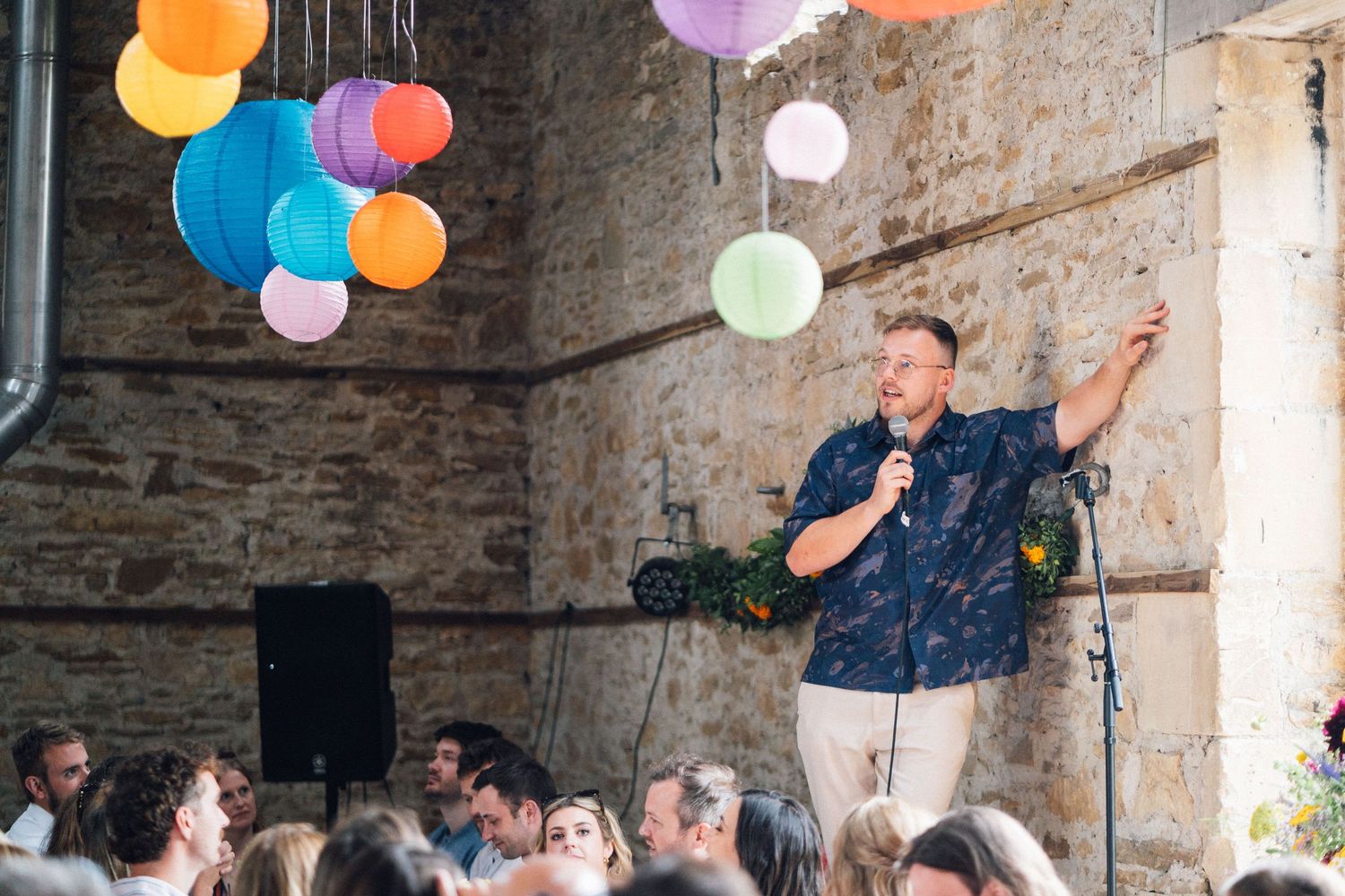 Colorful paper lanterns hang from the ceiling at an indoor wedding celebration.