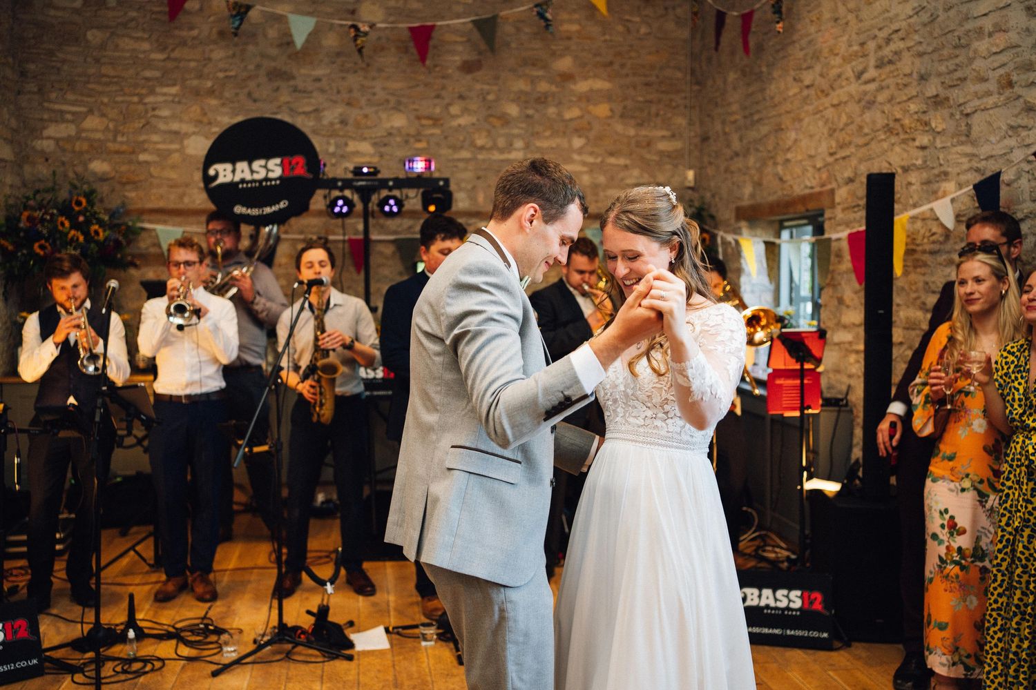 Couples dancing together at a wedding reception in a stone-walled venue with bunting decorations.