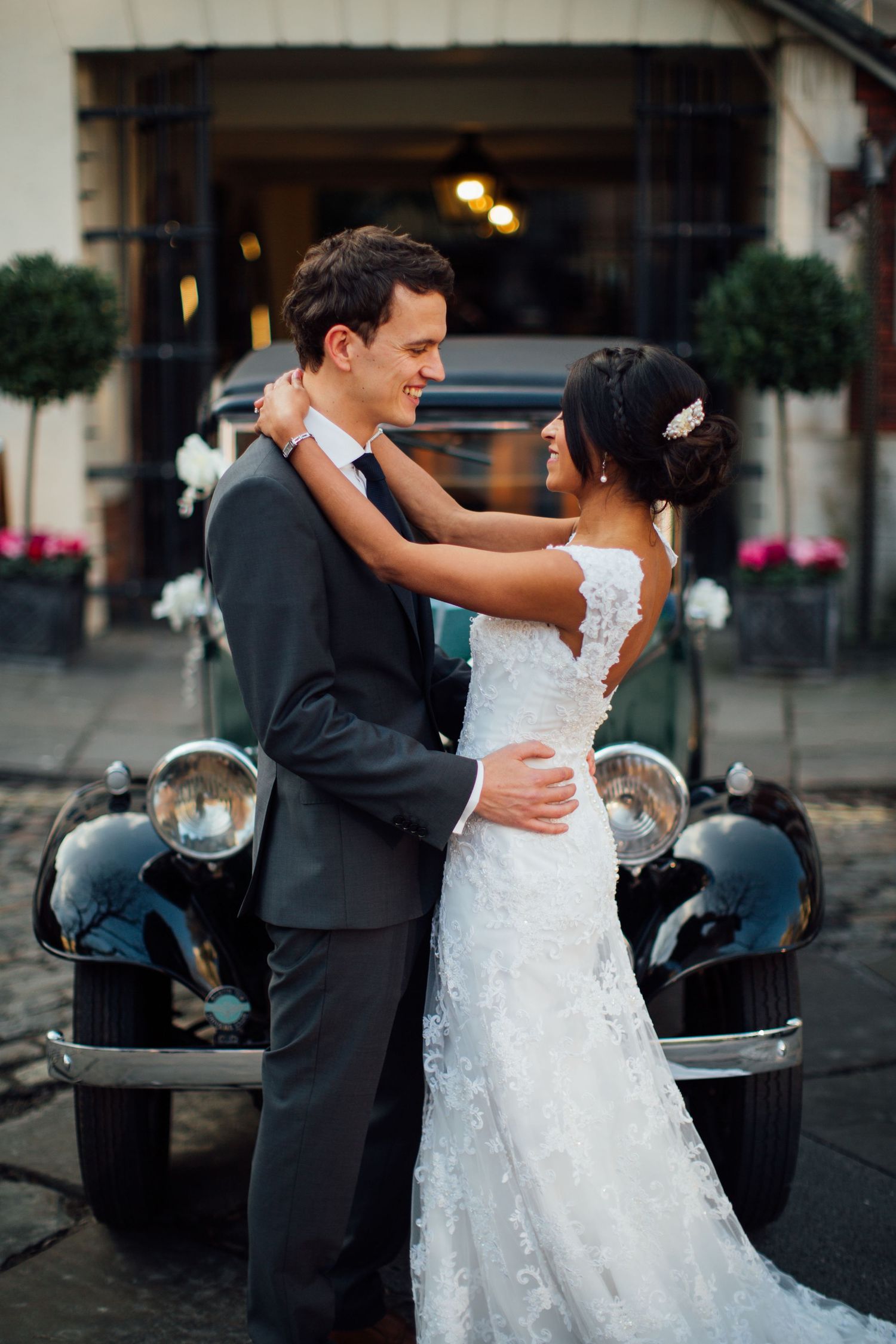 Couple dancing beside vintage car during evening wedding photoshoot.