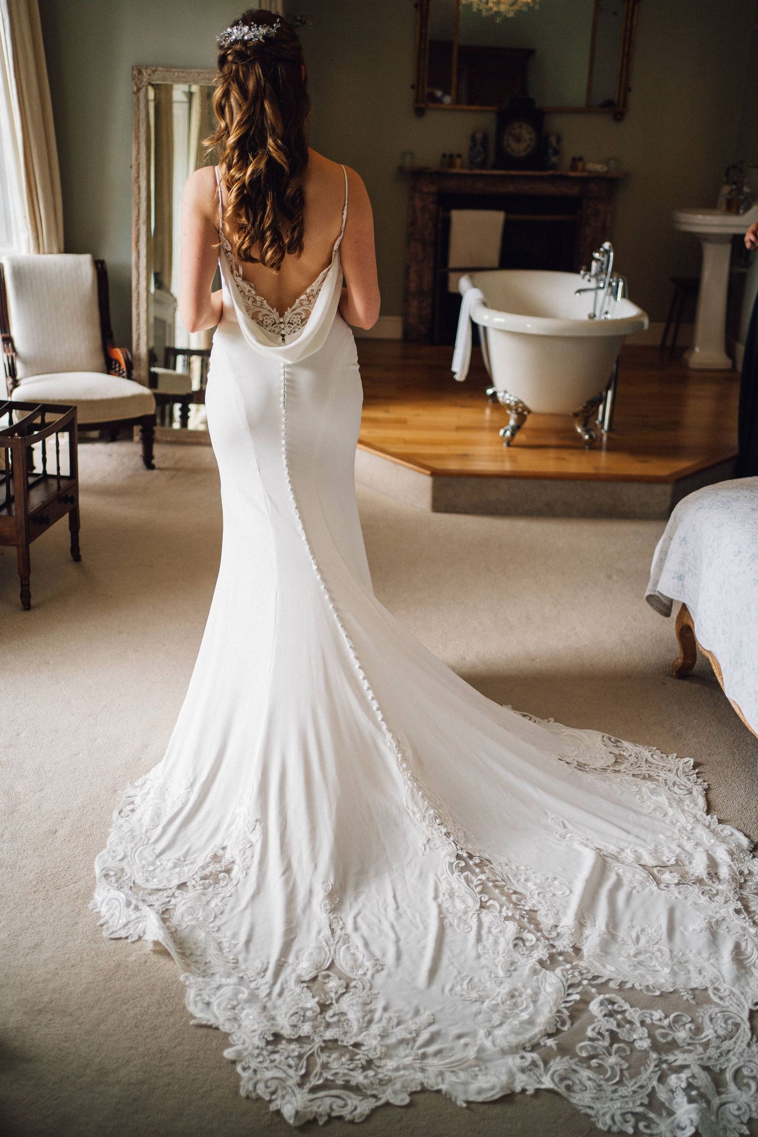 Beautiful white wedding gown with detailed lace train displayed in an elegant room.