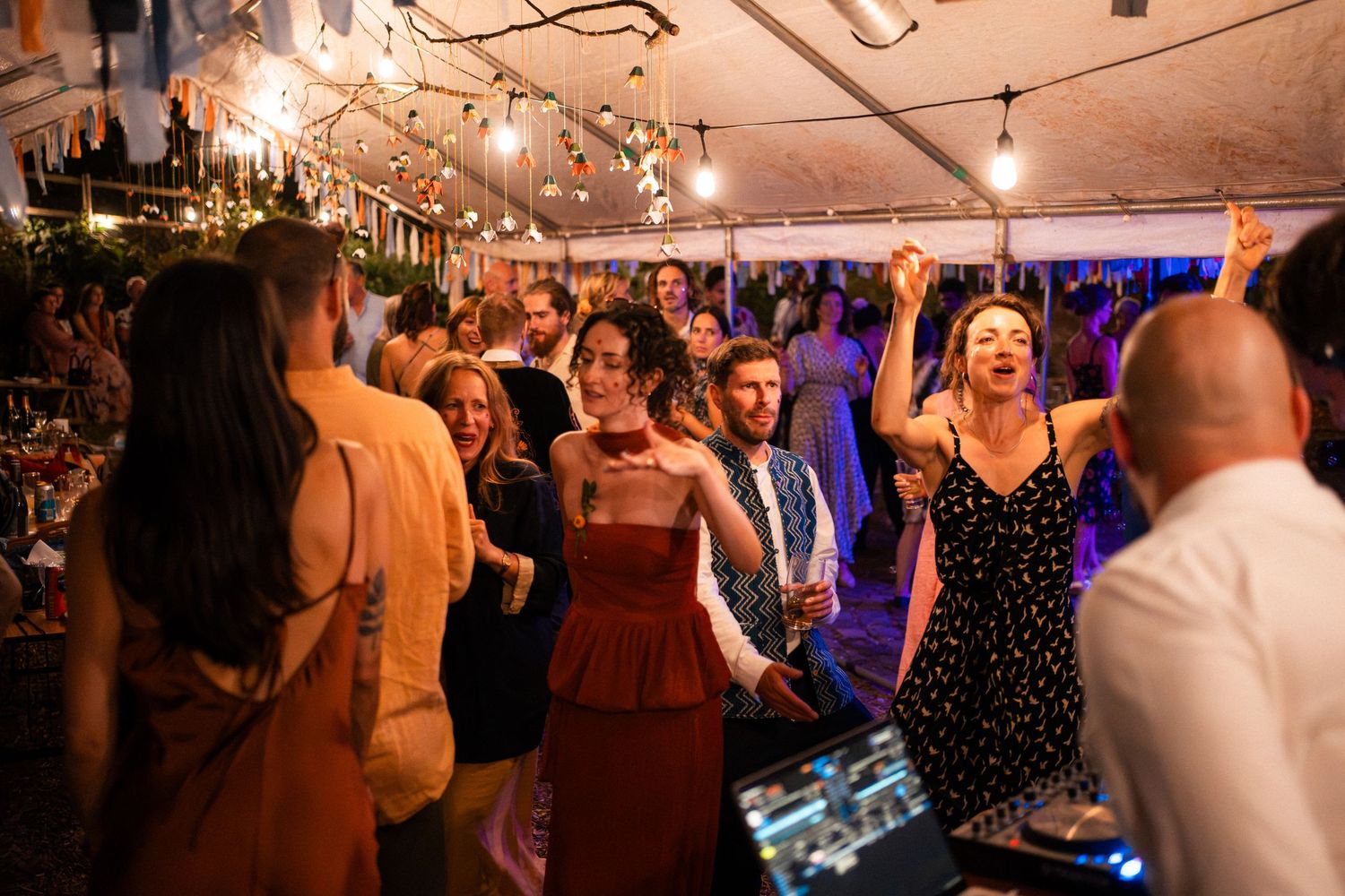 Guests dance energetically on the dance floor at an elegant wedding reception under warm lights.