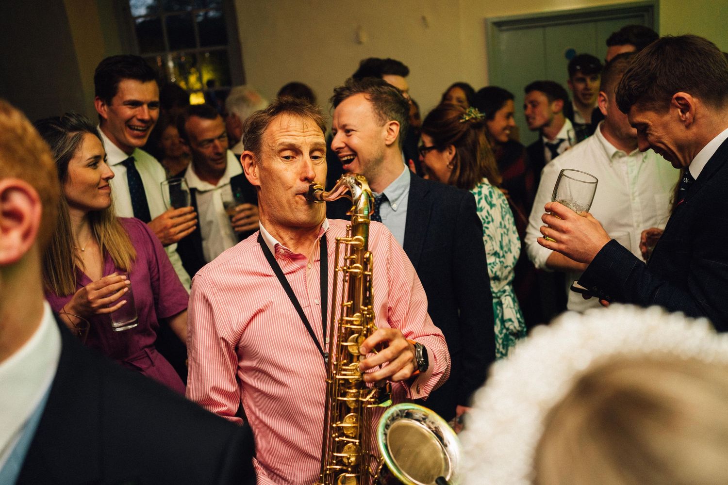 Wedding reception party with guests dancing and a saxophone player performing.