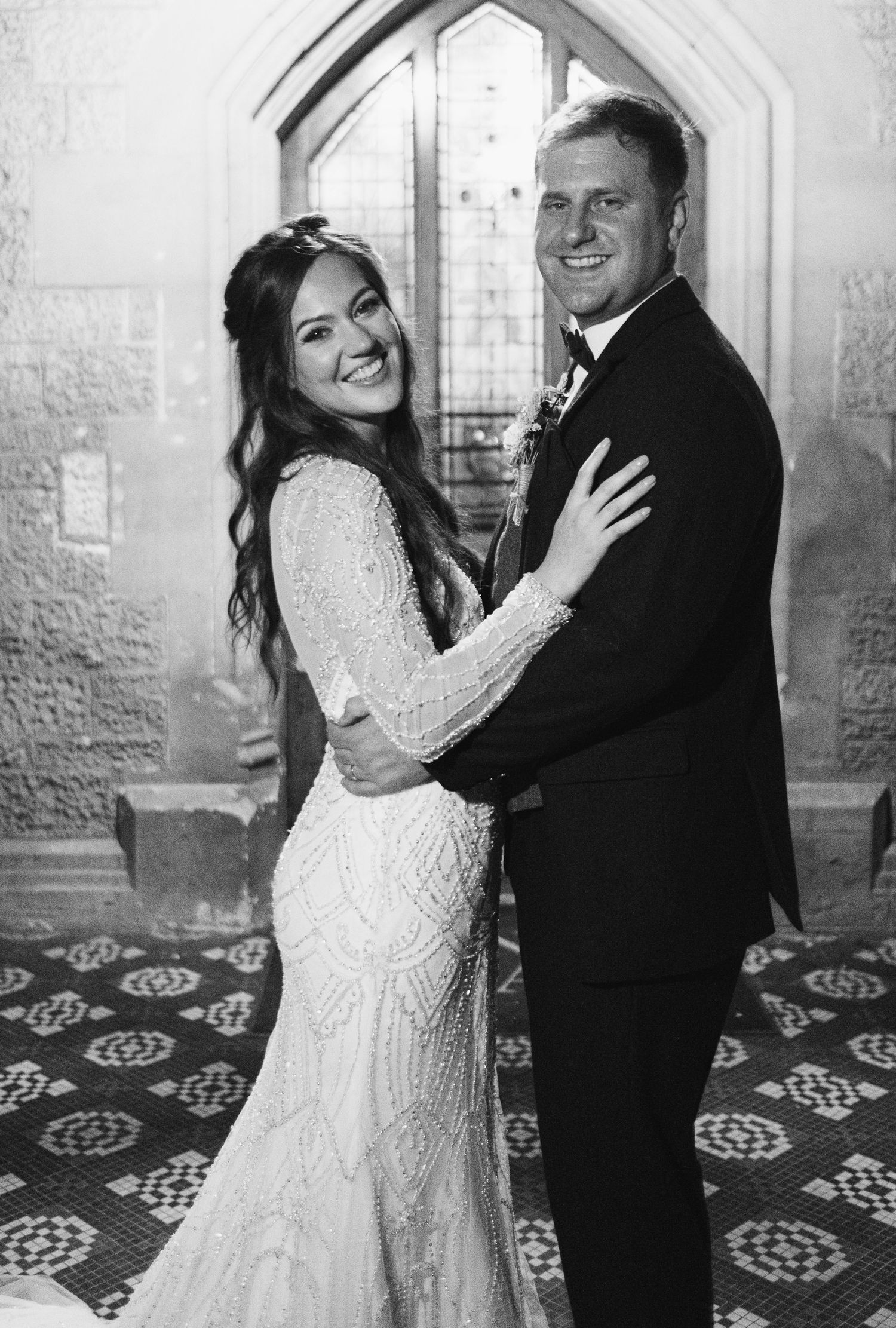 Joyful wedding portraits in vintage architectural setting with patterned floor.