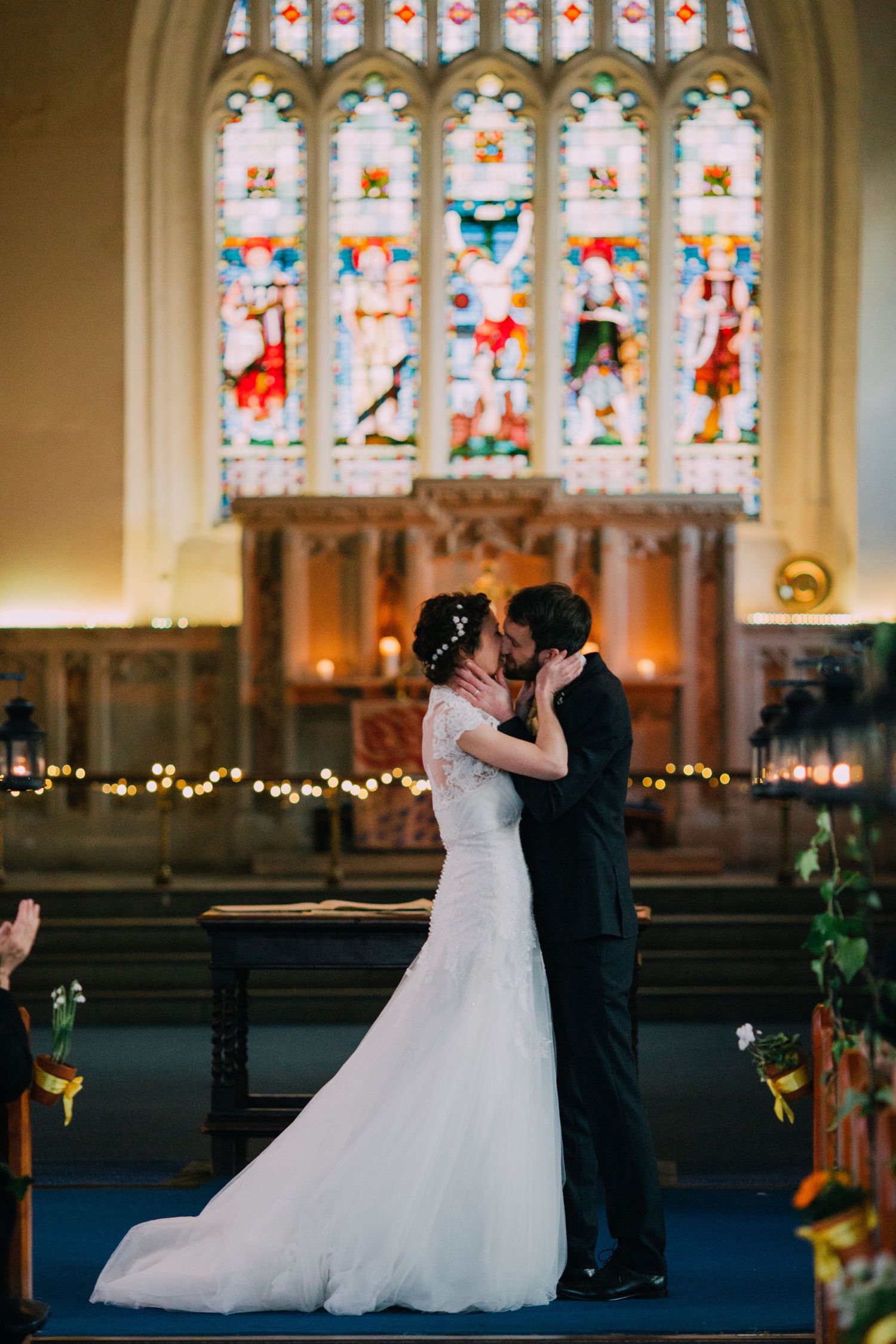 A romantic wedding moment captured in front of illuminated stained glass windows.