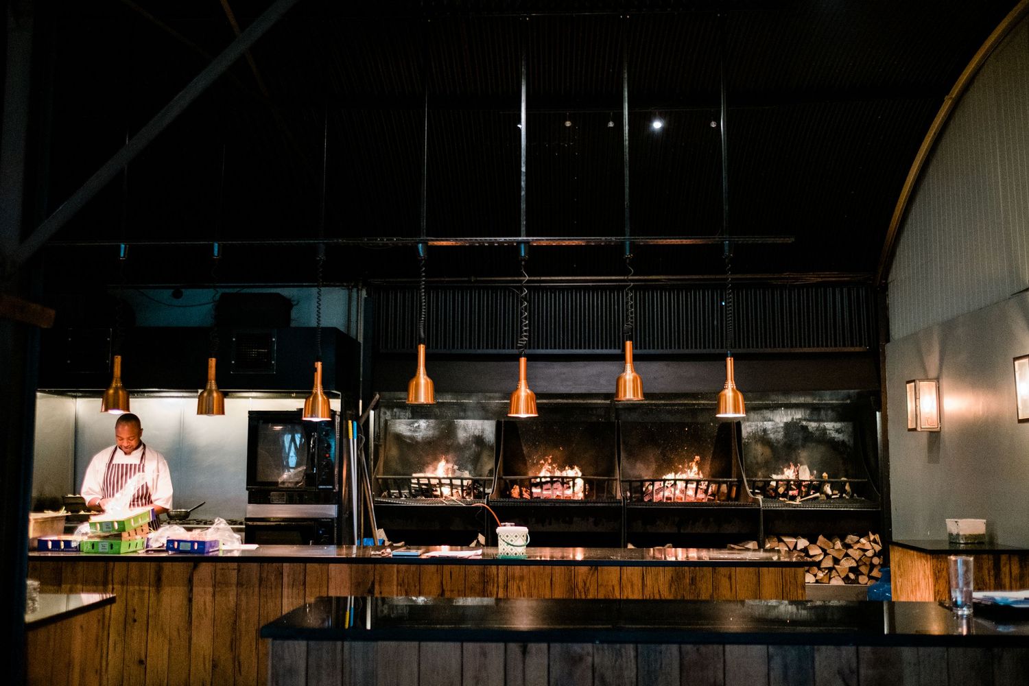 Dark interior of an event space with pendant lighting and wooden accents.