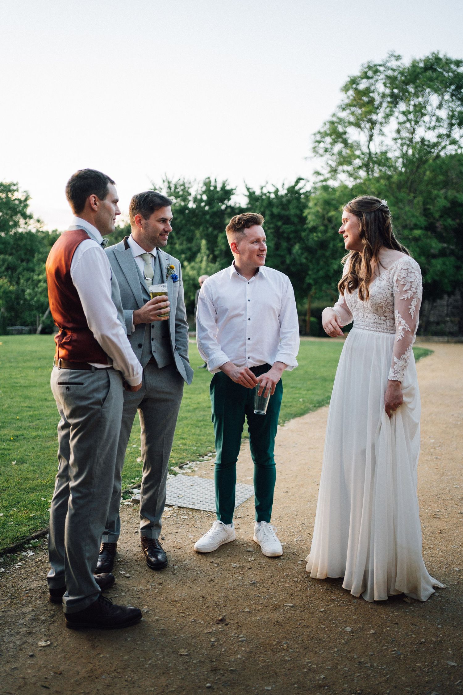 Wedding party gathered outdoors on a grassy hill during golden hour.