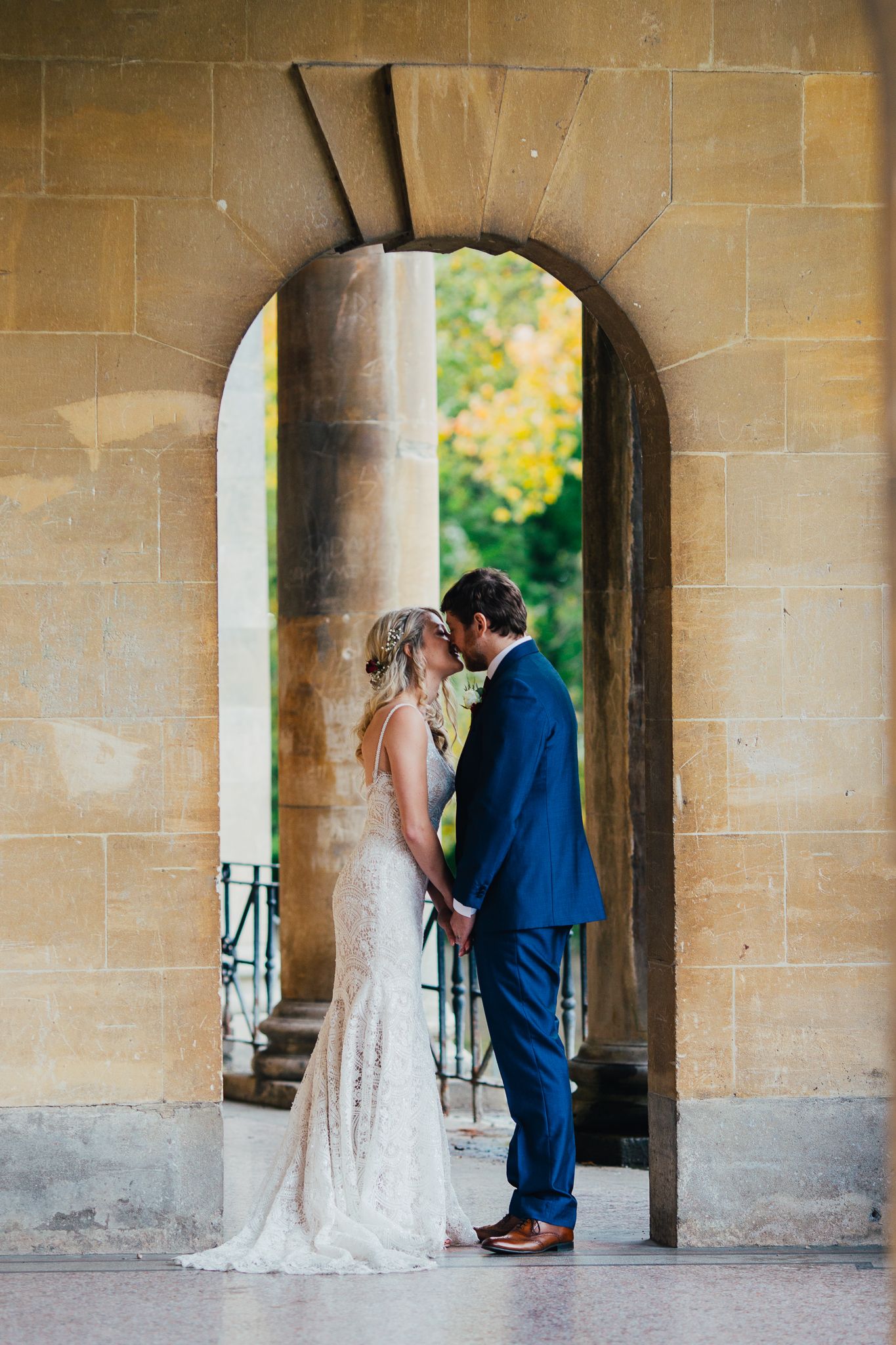 A romantic moment under stone archways with soft natural lighting.
